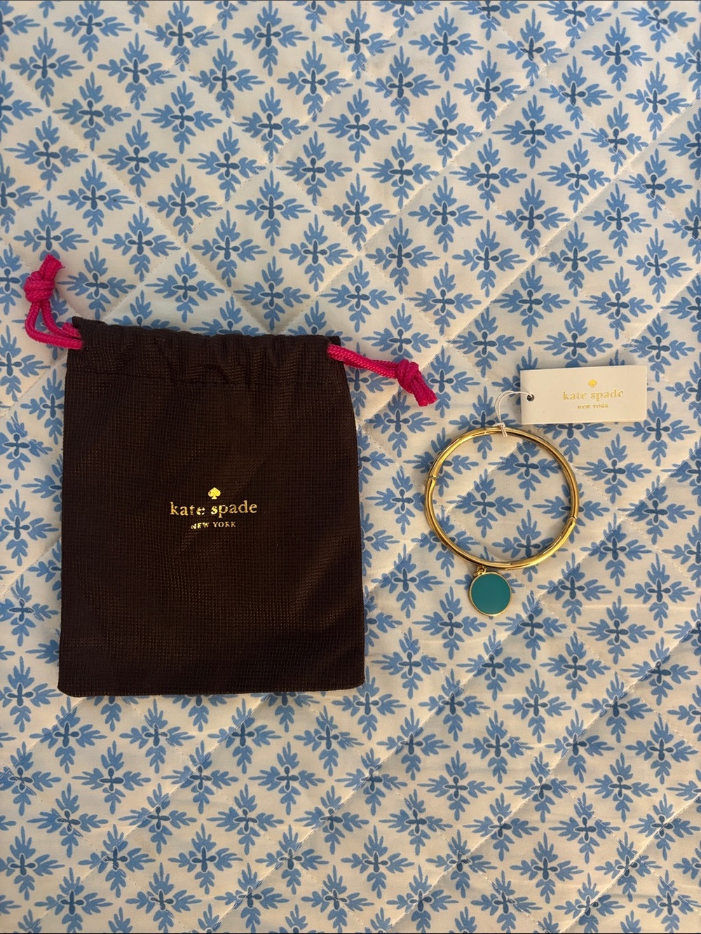 kate spade gold bangle with teal charm and brown pouch